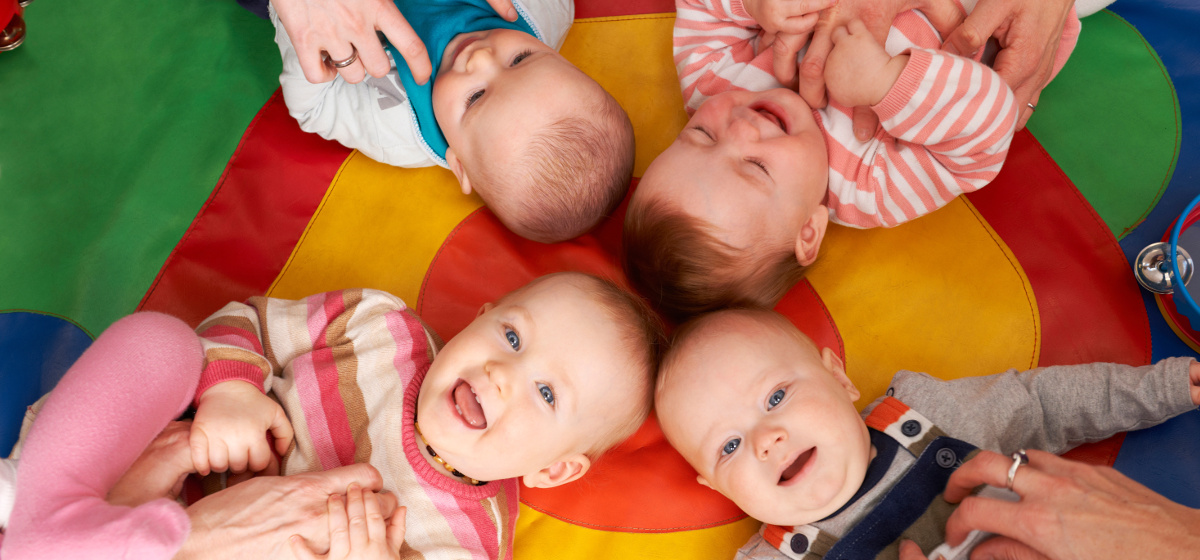 Photo de 4 bébés rigolant fasse aux chatouilles de leurs parents